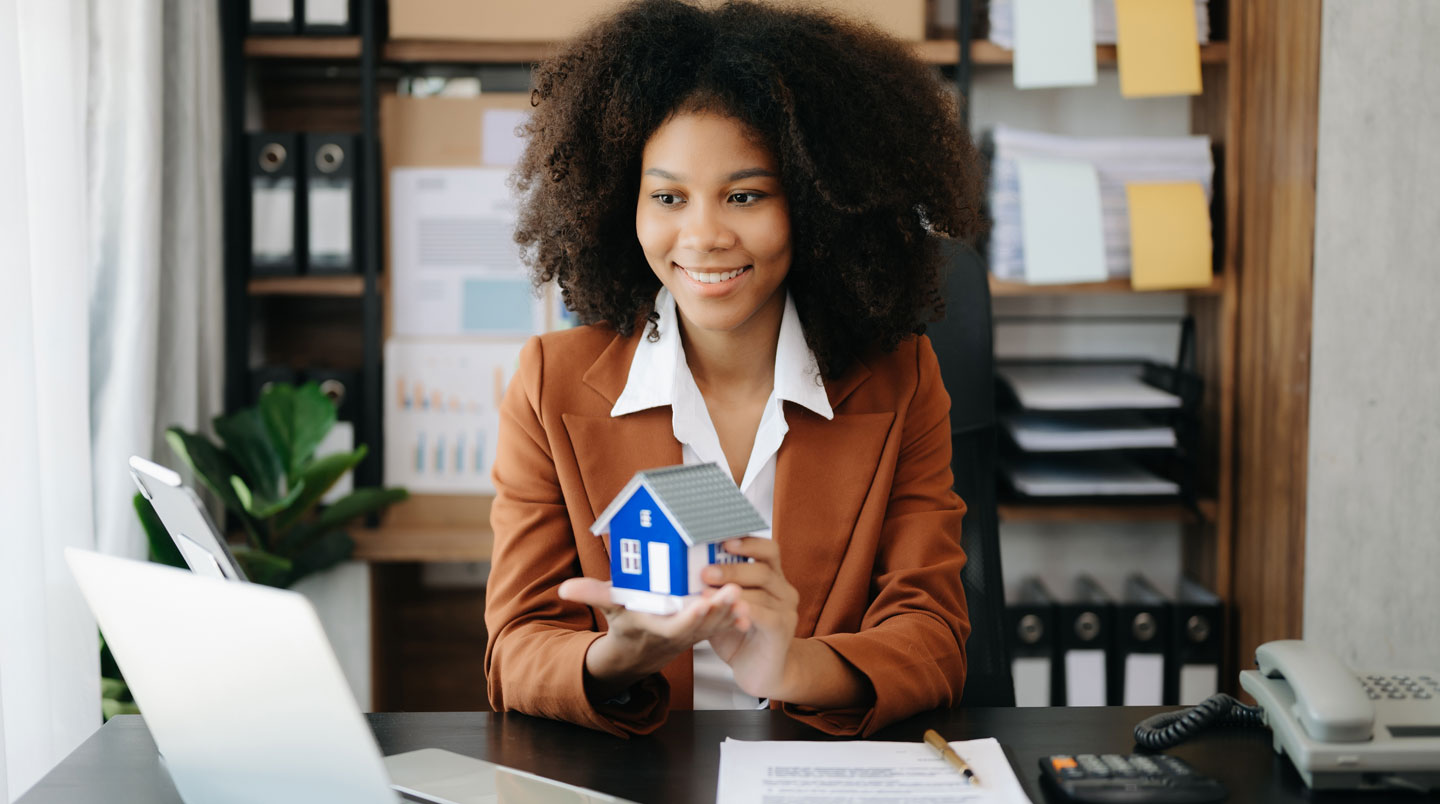 Femme consultant son téléphone et une tablette pour gérer un investissement immobilier à distance depuis son domicile